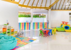 Světlá, barevná herna s&nbsp;malými stolky a&nbsp;židlemi, duhovou ohrádkou, pytli s&nbsp;fazolemi, pěnovými hracími podložkami, úložnými policemi a&nbsp;měkkou prolézačkou. Prostor je dobře osvětlený přirozeným světlem a&nbsp;moderně zařízený.