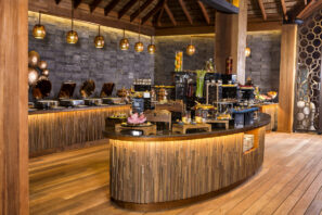 Stylový bufet s&nbsp;dřevěným a&nbsp;kamenným dekorem nabízí různé teplé a&nbsp;studené pokrmy, pečivo a&nbsp;dezerty pod teplými závěsnými světly, které vytvářejí příjemnou a&nbsp;elegantní atmosféru.