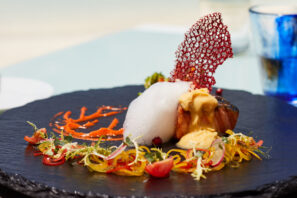 Gurmánský pokrm je umně položený na&nbsp;černé desce a&nbsp;obsahuje smaženou rybu s&nbsp;pěnou a&nbsp;omáčkou, ozdobenou barevnou zeleninou, mikrozeleninou a&nbsp;křupavou červenou taštičkou.